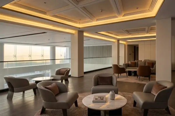 Desain interior lounge eksklusif di showroom mobil listrik premium Denza Haka Pondok Indah dengan pencahayaan hangat dan sofa minimalis modern.