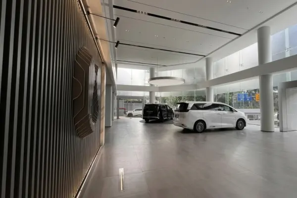 Desain interior showroom mobil listrik premium Denza Haka Pondok Indah menampilkan dua unit MPV mewah Denza D9 putih dan hitam dalam ruangan yang megah